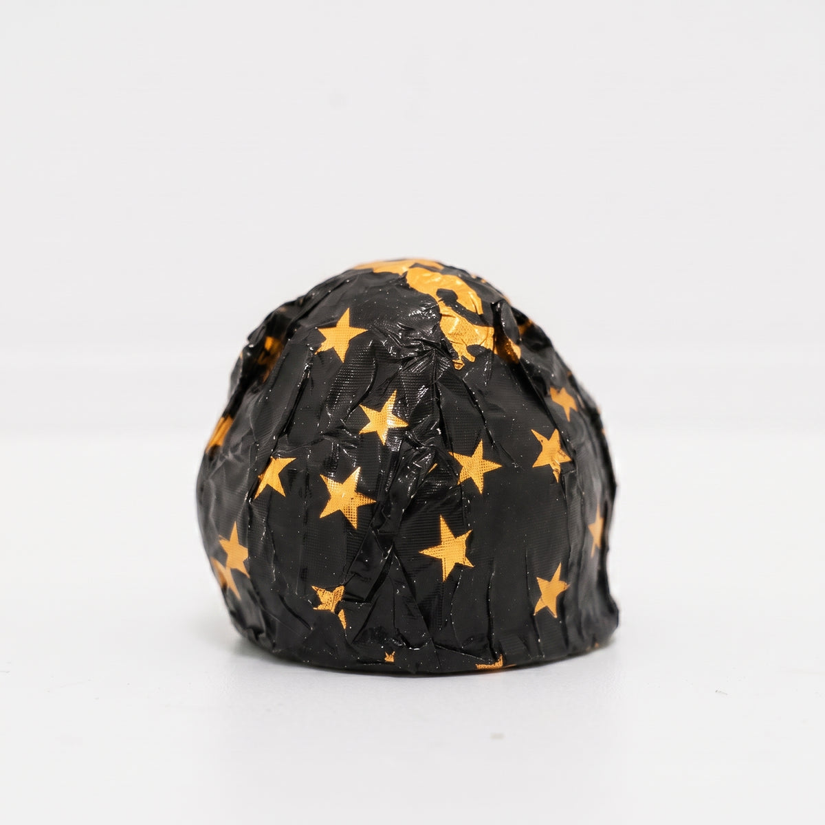A small black textured dome-shaped item covered in gold star patterns, photographed on a clean white background.