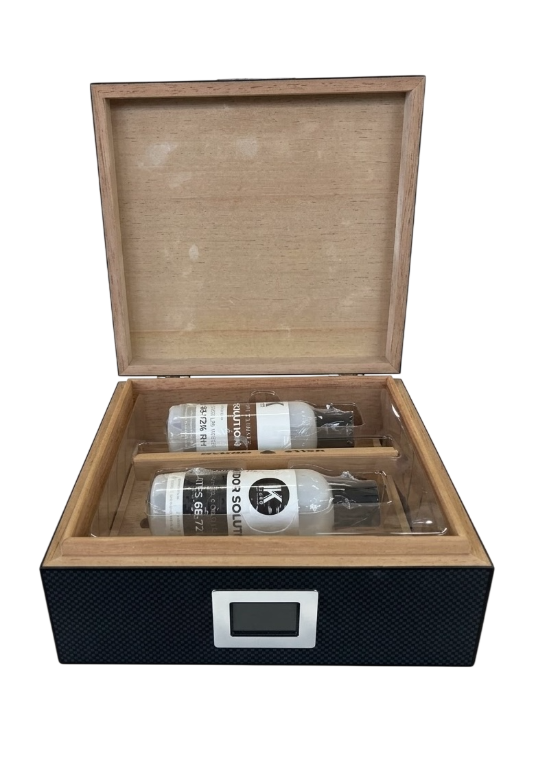 An open wooden humidor box with a black textured exterior and a silver label slot, containing two bottles of cigar tobacco on a white background.