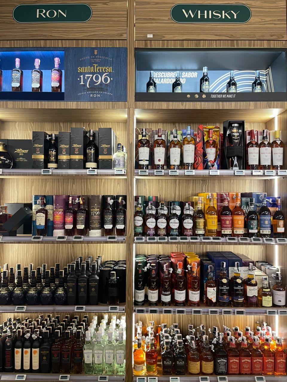 Anaqueles de ron y whisky en Grand Gourmet, con Santa Teresa 1796 y escoceses