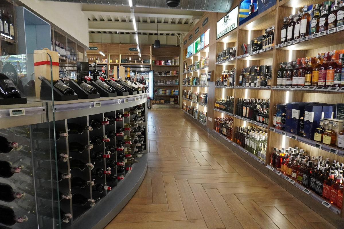 Pasillo de licores de Grand Gourmet con anaqueles de whisky, ron y vinos iluminados