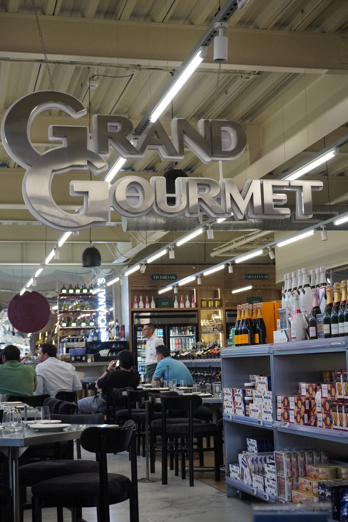 Interior de Grand Gourmet en Las Mercedes, Caracas: letrero, gastronomía y delicateses y mesas del área de tapas